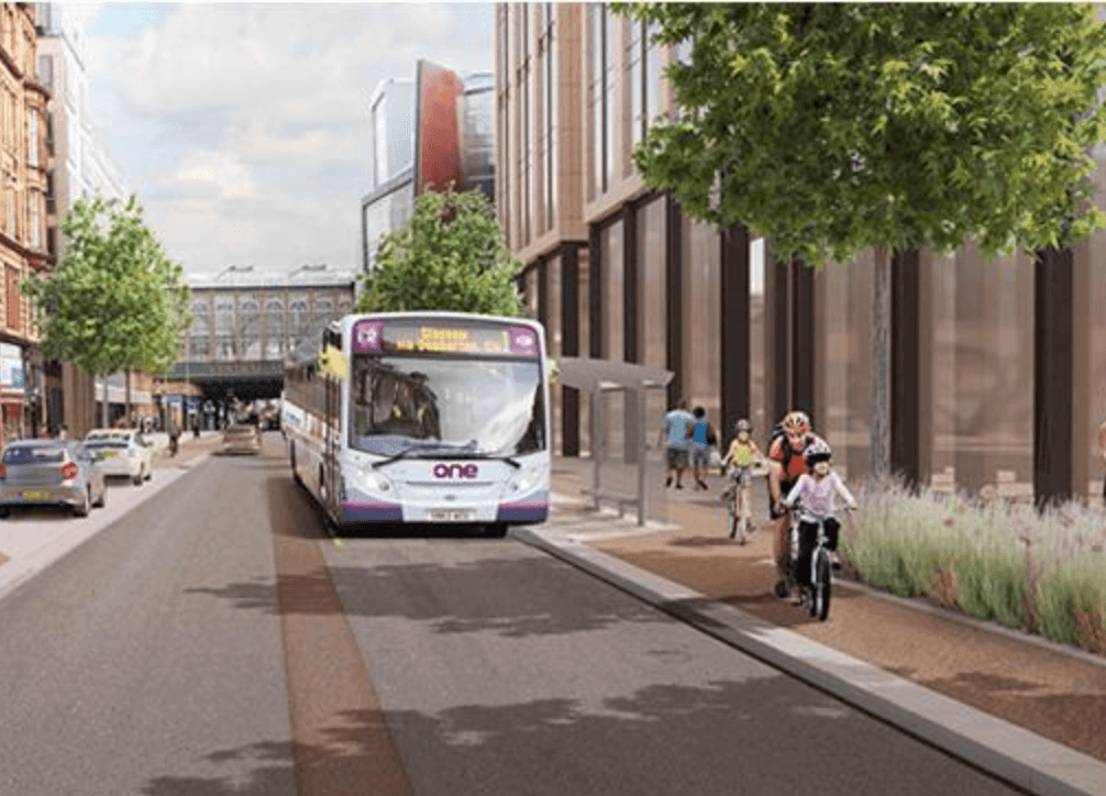 White bus driving through a modern city street with cyclists on a dedicated side path.
