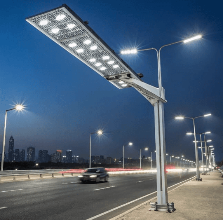 Modern solar-powered LED street light illuminating a highway at night with a distant city skyline.