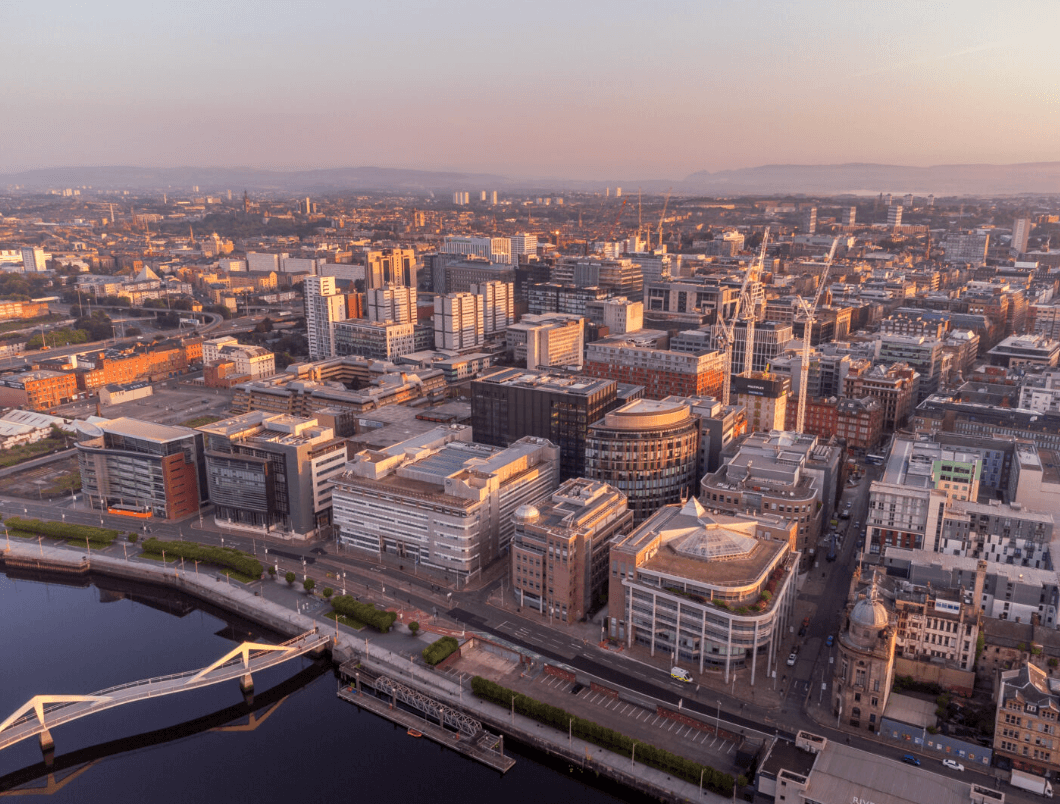 Aerial sunset view of Glasgow city skyline, River Clyde, and Tradeston Bridge in golden light.