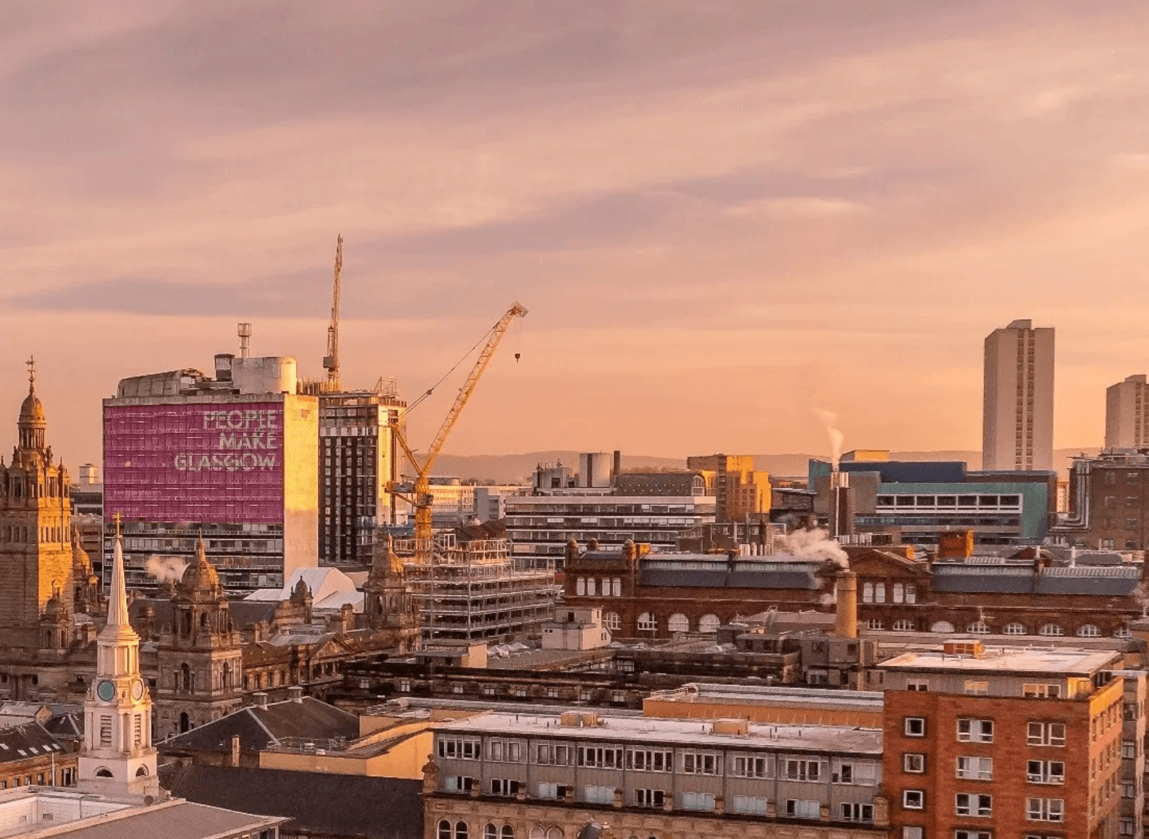 Glasgow cityscape at sunset featuring the iconic pink People Make Glasgow sign and cranes.